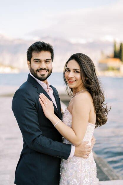 Premium Photo Smiling Groom Stands Hugging Bride Waist By The Sea