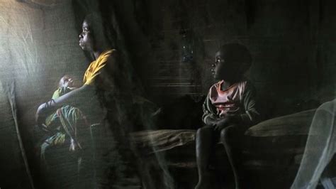 Two People Sitting In A Dark Room With Curtains On The Wall And One