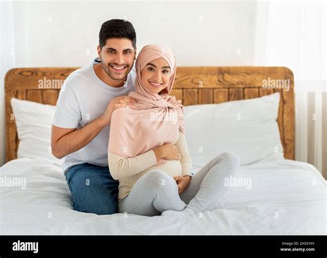 Caring Arab Husband Massaging His Pregnant Wifes Shoulders At Home Sitting Together On Bed And