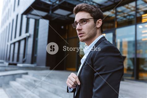 Business Man In Suit And Glasses Standing Sideways Near The Office