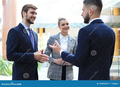 Three Young Businessmen Standing Discussing Business At An Office