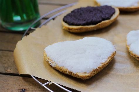 Four Cookies With White And Black Frosting Are On A Tray Next To A