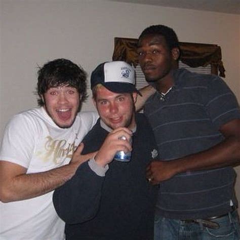 Three Men Standing Next To Each Other And One Holding A Beer In His