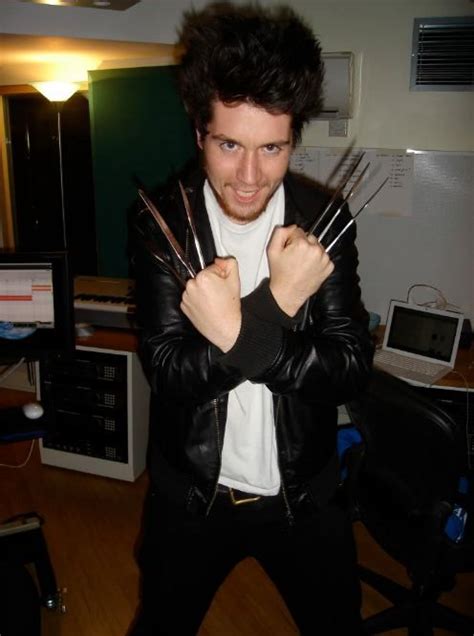 A Man In A Leather Jacket Holding Up Four Pairs Of Scissors