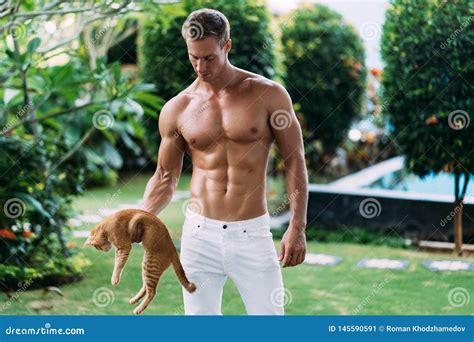 Portrait Of Athletic Man In White Pants With Naked Torso Holds Ginger