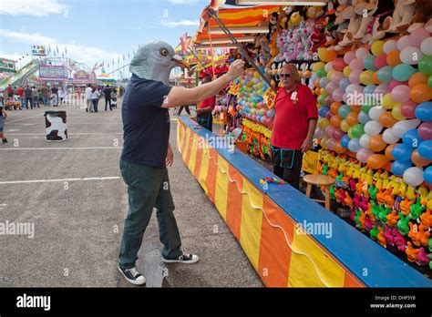 Man wearing pigeon mask aims dart at balloons, New Mexico state fair ...