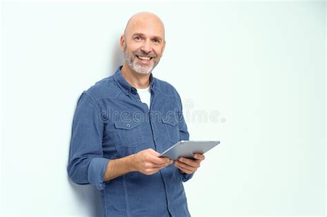 Cheerful Bald Mature Man With Digital Tablet In Hands Smiling Looking