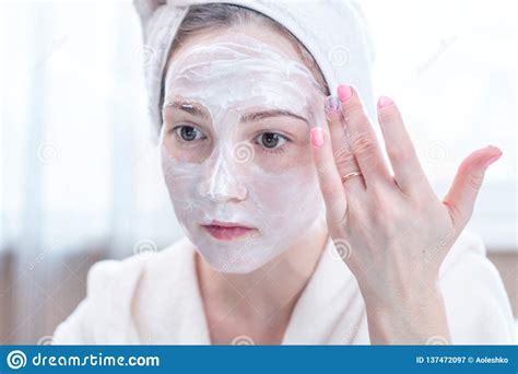 Happy Woman Applying Cream On Face Moisturizing The Skin Concept Of