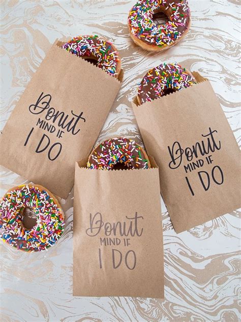 Four Donuts With Sprinkles In Brown Paper Bags That Say Donut Mind Do