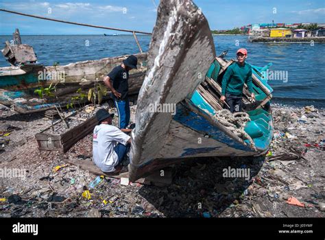 Men repairing wooden fishing boat on the land fill beach of Cilincing, North Jakarta, Indonesia ...