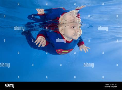 Litle Boy In Superman Costume Posing Under Water In Swimming Pool