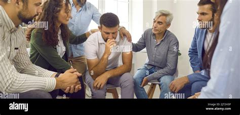 People Supporting And Comforting A Depressed Young Man During A Group