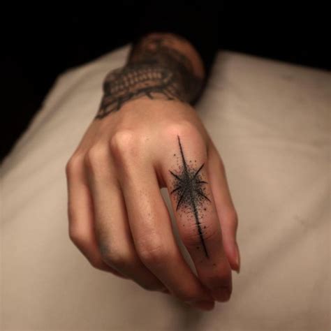 A Person With A Star Tattoo On Their Left Hand Holding Onto A Pillow