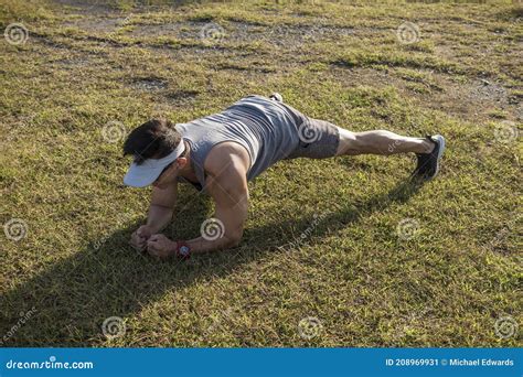 A Asian Guy Does Planks On The Grass At A Park Outdoors Core And