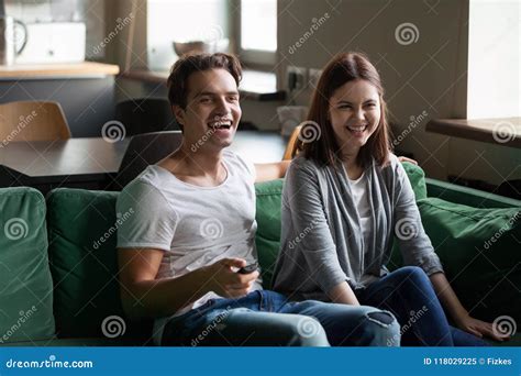 Millennial Couple Laughing Watching Tv Holding Remote Control At Stock