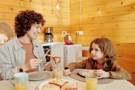 Happy Young Woman Spreading Peanut Butter On Roasted Toast Stock Image