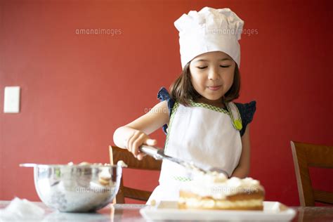 ケーキにクリームを塗っている女の子[10568009592]の写真素材・イラスト素材｜アマナイメージズ