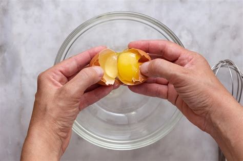 Premium Photo Top View Of Woman Hand Cracking Raw Brown Egg Into