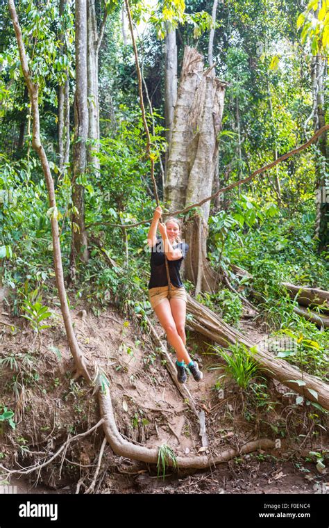 Young Woman Swinging On A Vine In The Jungle Tropical Rain Forest