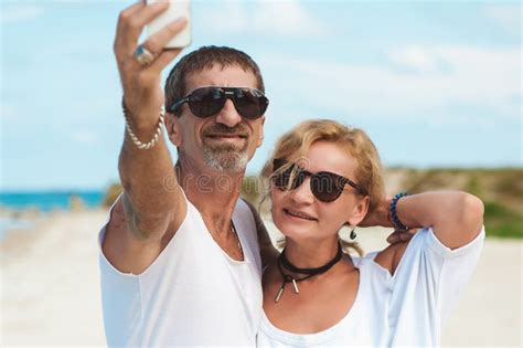 Portrait Of Mature Smiling Couple Taking A Selfie At The Beach Stock