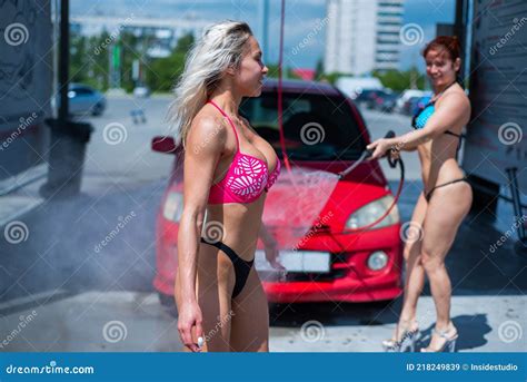 Luxury Girls In Seductive Bikinis Wash A Car In A Street Car Wash And Water Each Other Blonde