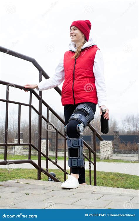 Woman Wearing Knee Brace Or Orthosis After Leg Surgery Walking In The