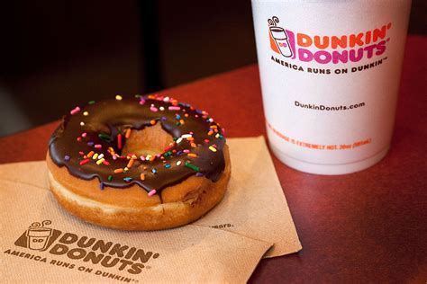 A Donut Sitting On Top Of A Napkin Next To A Cup Of Dunkindonuts