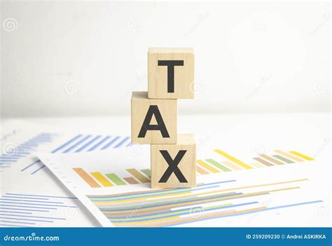 Wooden Cubes With The Word Tax On Financial Background With Chart Stock