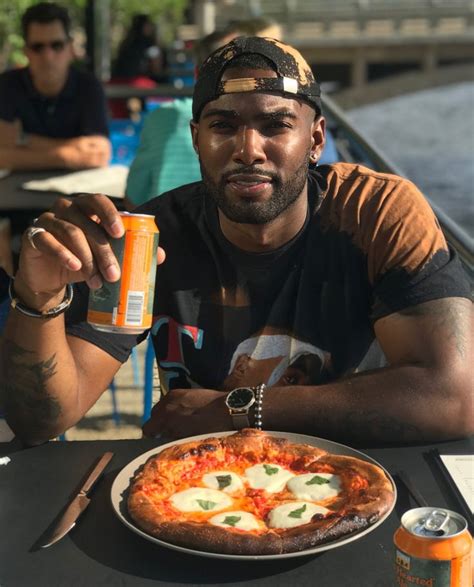 A Man Sitting At A Table With A Pizza And Drink