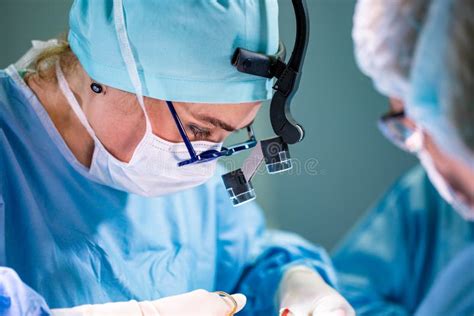 Surgeon And His Assistant Performing Cosmetic Surgery On Nose In