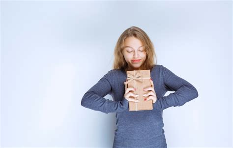 Fille Blonde Démontrant Sa Boîte cadeau En Carton Et Se Sentant Positive Photo Gratuite