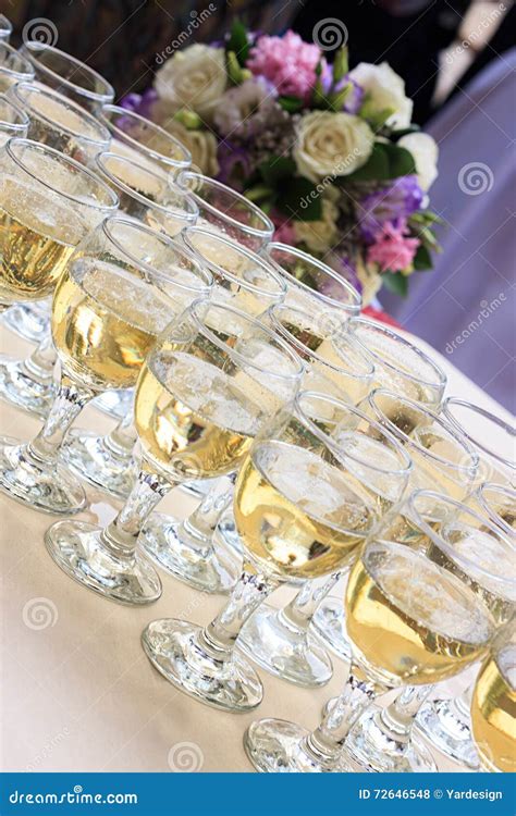 Rows Of Champagne Glasses On Table With Beautiful Bouquet On Colorful Tablecloth And Rustic