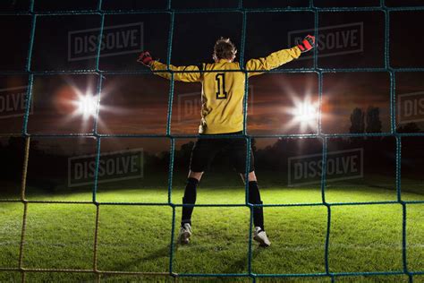 Full length rear view of goalie defending soccer net on field - Stock Photo - Dissolve