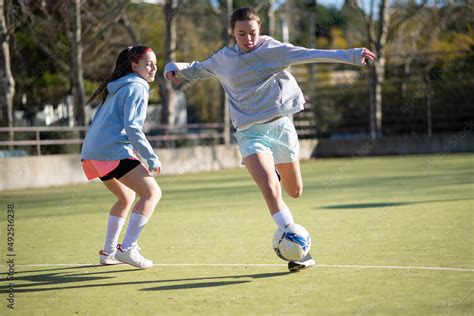 Happy girls playing football on sunny day. Two young girls in ...