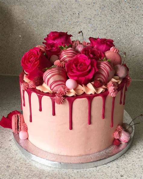 A Cake With Pink Icing And Roses On Top Is Sitting On A Countertop