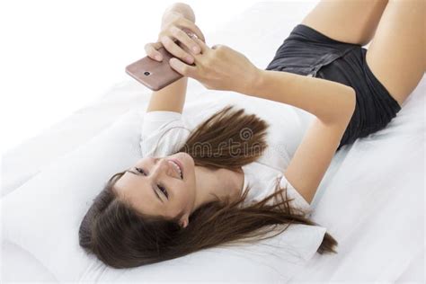 Chica Joven Hermosa Que Manda Un Sms Mientras Que En Cama Foto De