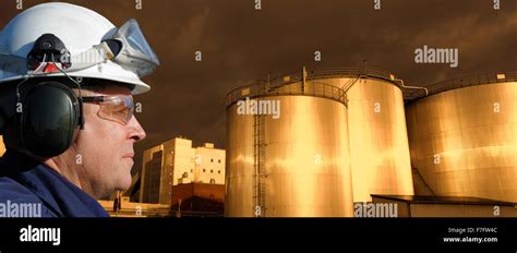 Oil And Gas Worker With Large Fuel Tanks Refinery Tanks In Background