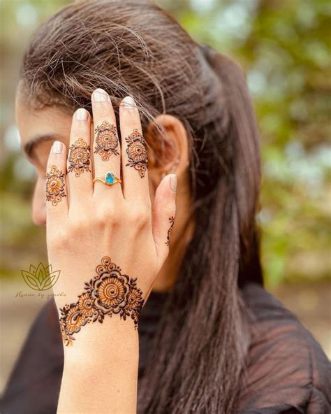 A Woman With Henna Tattoos Covering Her Face And Holding Her Hand Up To Her Face