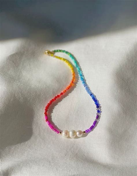 A Multicolored Beaded Necklace On A White Cloth With Pearls Hanging From It