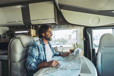 Happy Mature Man Smilng Inside A Camper Camping Car Using Paper Map Guide To Plan Destinations