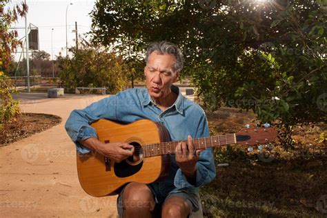 Happy Mature Man Singing And Playing His Acoustic Guitar In The Park