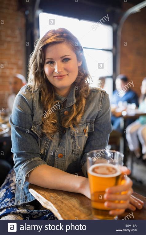 Portrait of smiling woman drinking beer in pub Stock Photo - Alamy