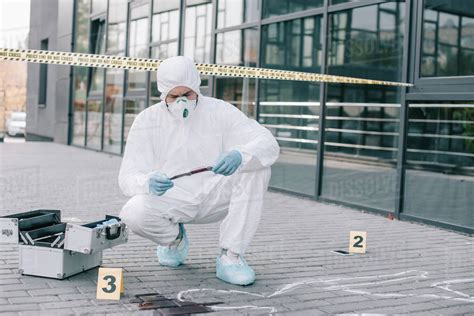 Male Criminologist In Protective Suit And Latex Gloves Explore The