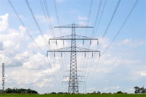 Electric High Voltage Pole On Green Meadow With Blue Sky Background