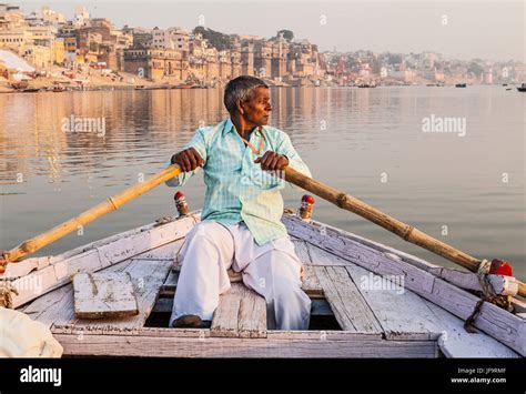 A Indian Man Rowing A Boat For Tours On The Ganges River Varanasi