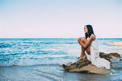 Belle Fille Assise Sur Un Rocher Sur La Mer De La Plage Photo Premium