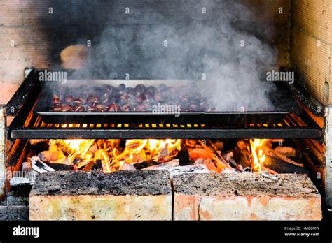 Roasting Grilled Chestnuts On Barbecue With Flames Fire And Charcoal