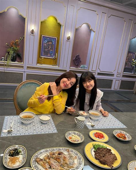 Two Women Sitting At A Table With Plates Of Food In Front Of Them