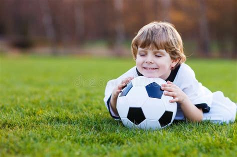 Blonde Jongen Van Speelvoetbal Met Voetbal Op Voetbalgebied Stock Foto Image Of Spel