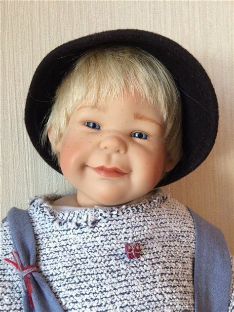 A Doll With Blonde Hair And Blue Eyes Wearing A Black Hat On Top Of Her